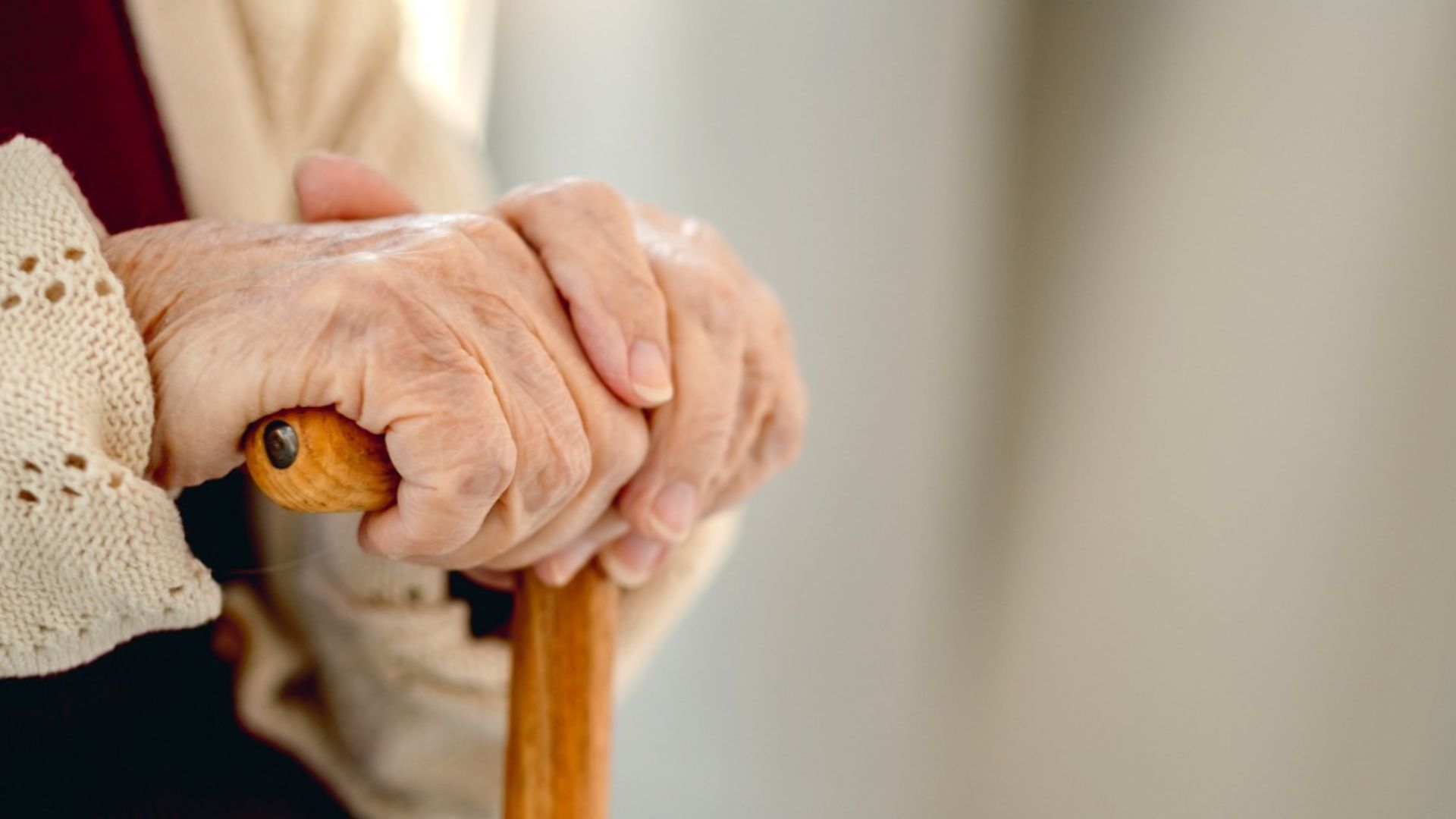 Adulto mayor apoyado en un bastón color café