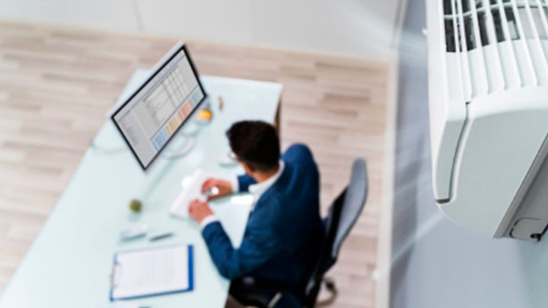 Un hombre de espaldas trabaja en un computador.