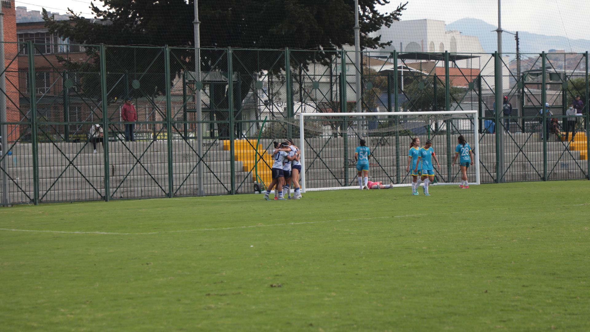Cancha de fútbol con jugadoras de uniforme azul
