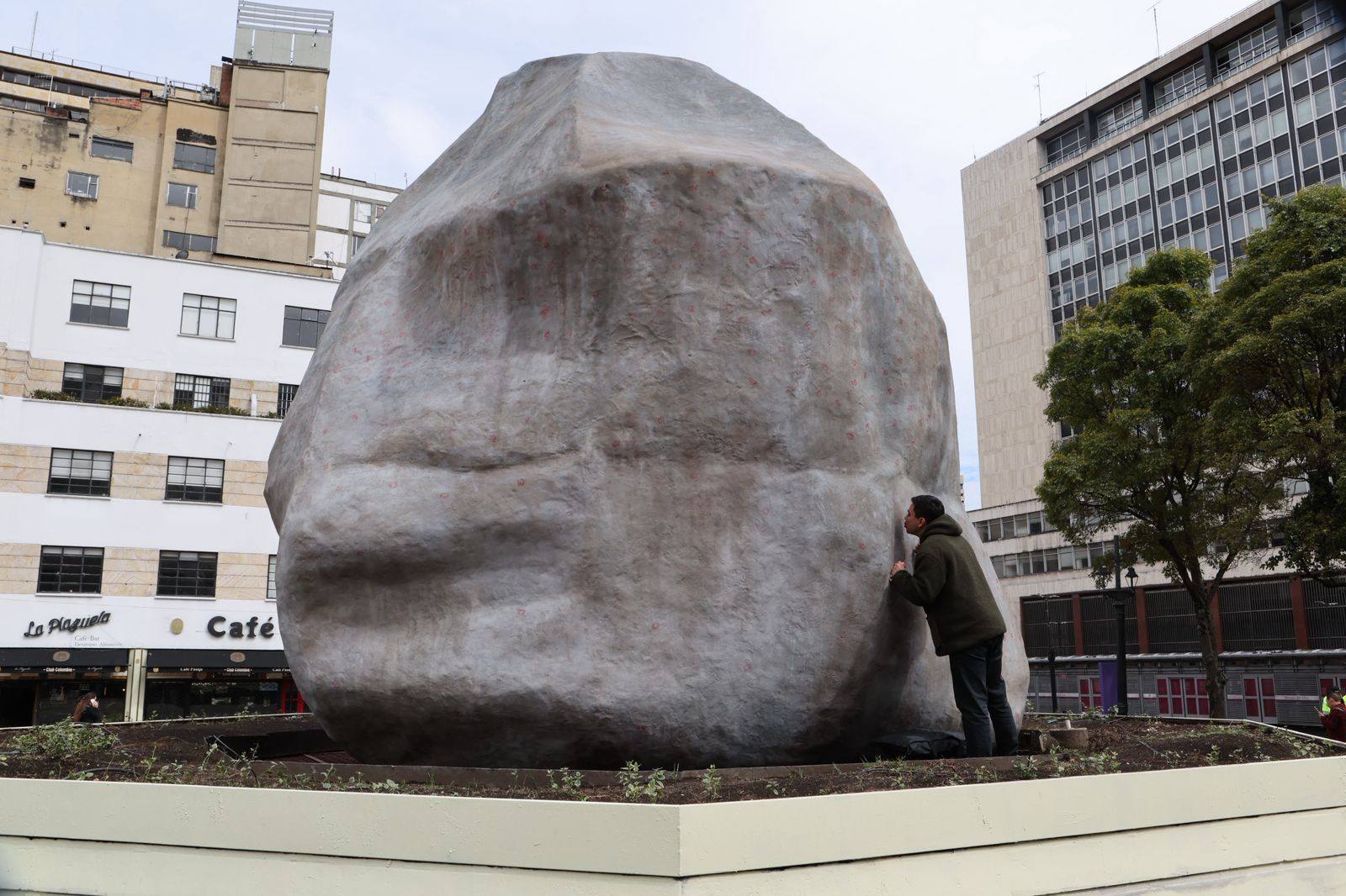 Foto de la obra Dándole peso a unos besos, ubicada en la plazoleta del Rosario. A la derecha, un hombre le da un beso a la escultura.