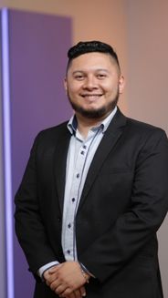 Alexander Vera- periodista hombre en plano americano con camisa azul clara y blazer negro