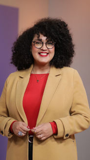 Jenny Bastidas- periodista, mujer en plano americano con afro, blusa roja y blazer color mostaza