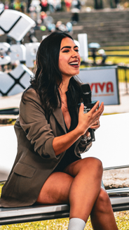 Jessica Bohórquez- presentadora. Mujer en plano americano con un micrófono en la mano y blazer café