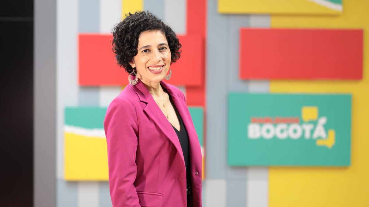 Magda Páez Torres, en el set de Hablemos Bogotá, con una chaqueda rosada y camisa negra.