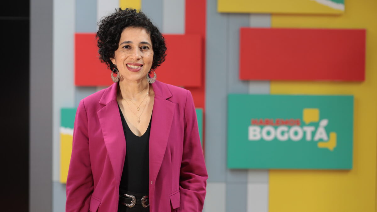Magda Páez Torres, en el set de Hablemos Bogotá, con una chaqueda rosada y camisa negra.