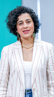 Magda Páez Torres, periodista de Hablemos Bogotá. Vestida con un saco blanco con lineas rosadas.