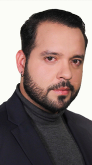 Foto de Jose Chinchilla hombre en plano medio con buzo con cuello de tortuga gris y blazer azul oscuro